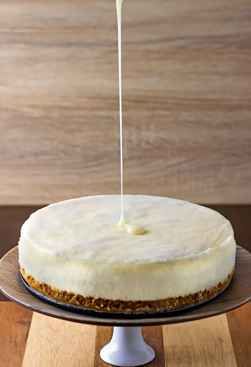 Pouring white chocolate ganache onto cheesecake
