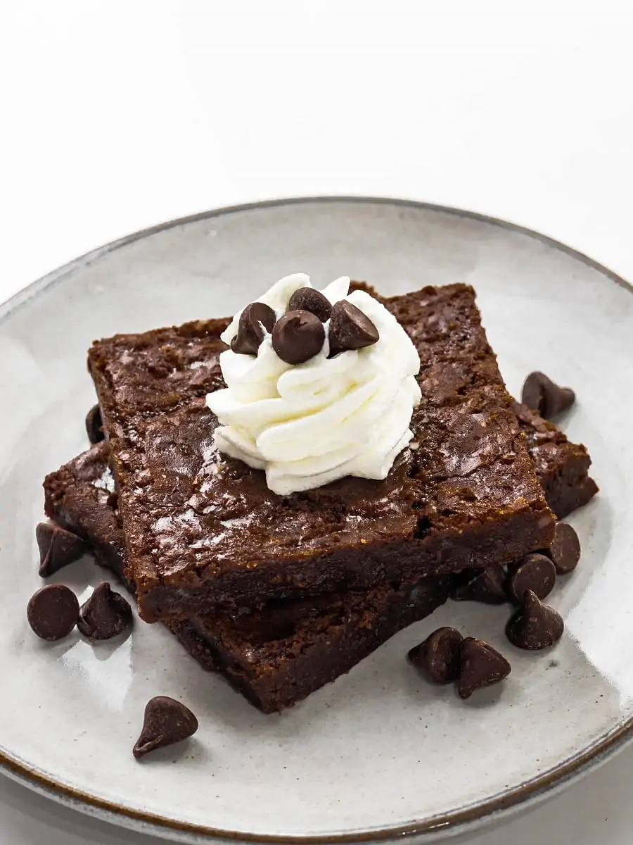 Almond Flour Brownies on a Plate with Whipped Cream and Chocolate Chips