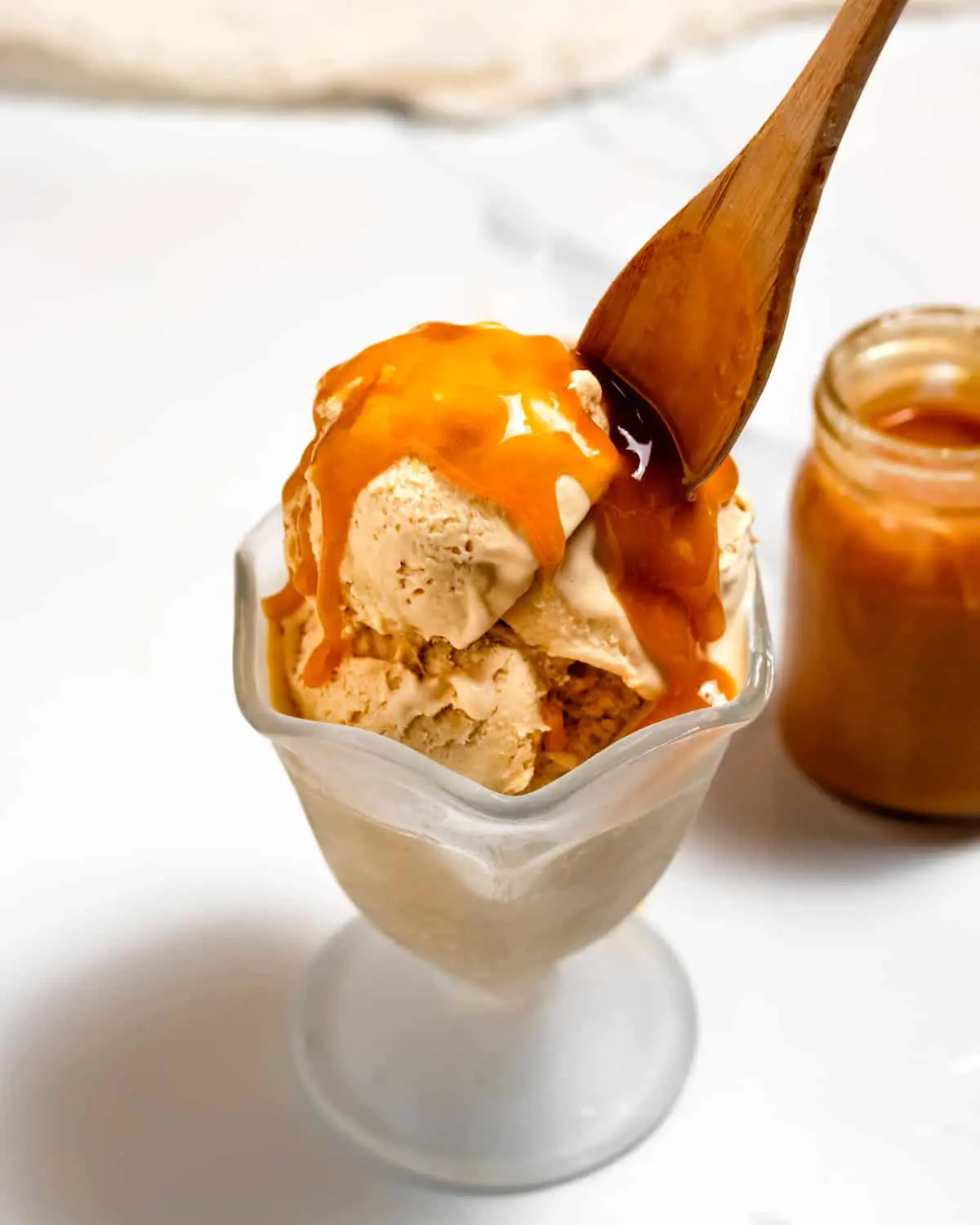 butterscotch ice cream in ice cream bowl with wooden spoon