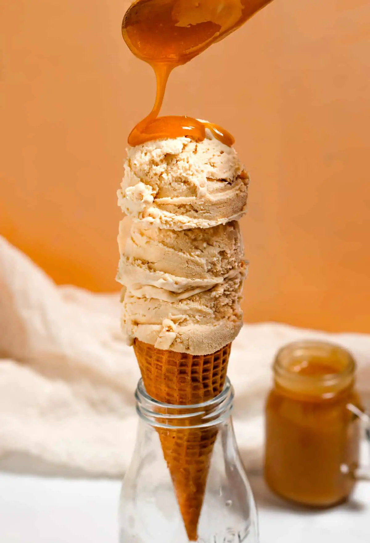 drizzling butterscotch sauce on ice cream in cone