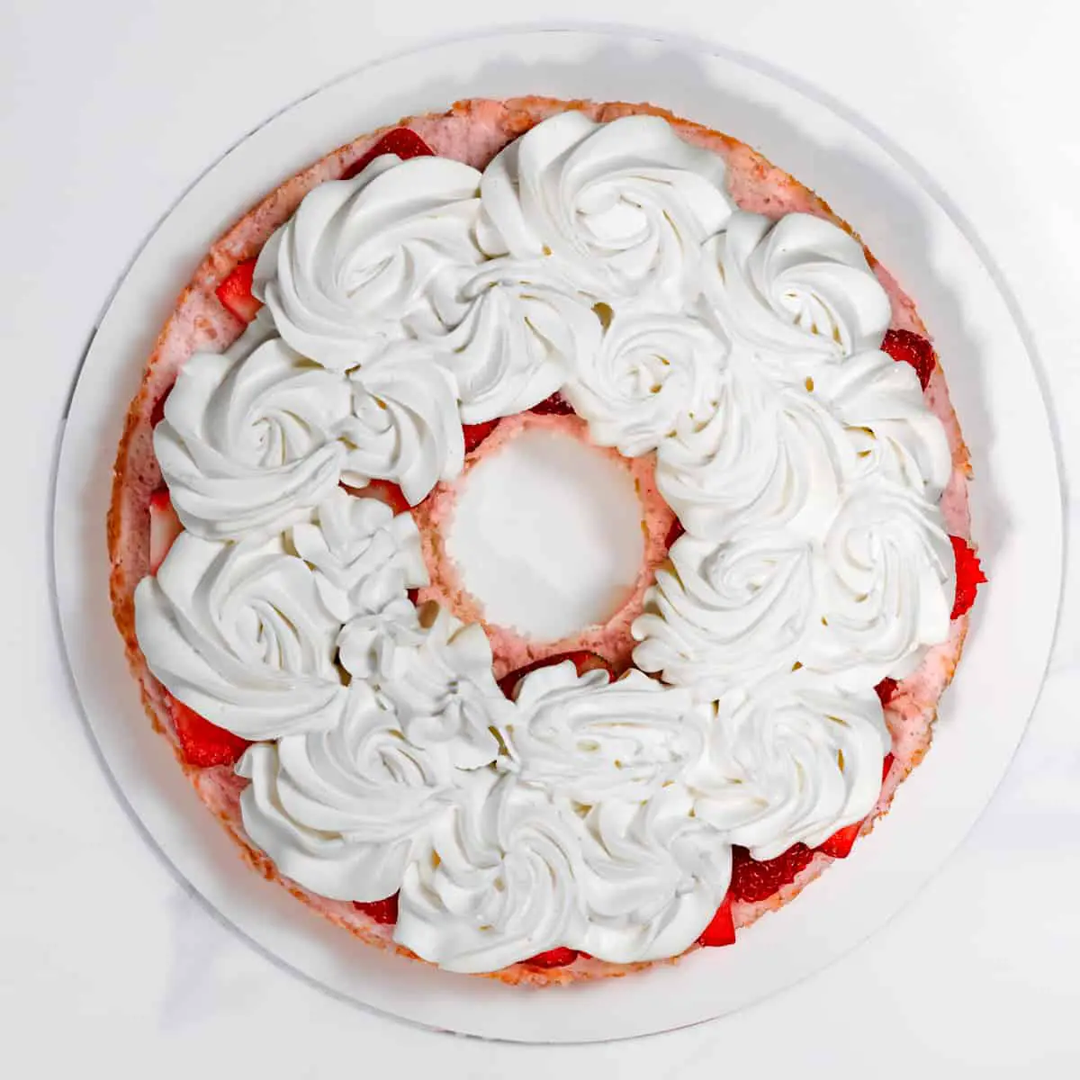 adding whipped cream and strawberries to angel food cake